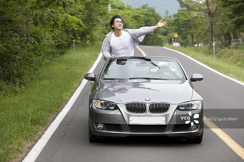 站在行驶中的敞篷车里的男人图片素材