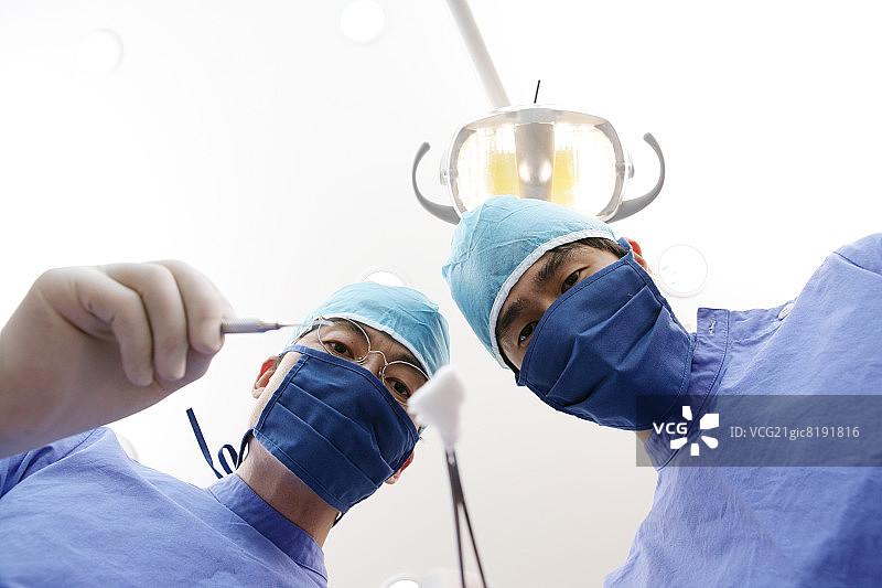 牙医和牙科助手拿着拔牙钳的仰视肖像图片素材
