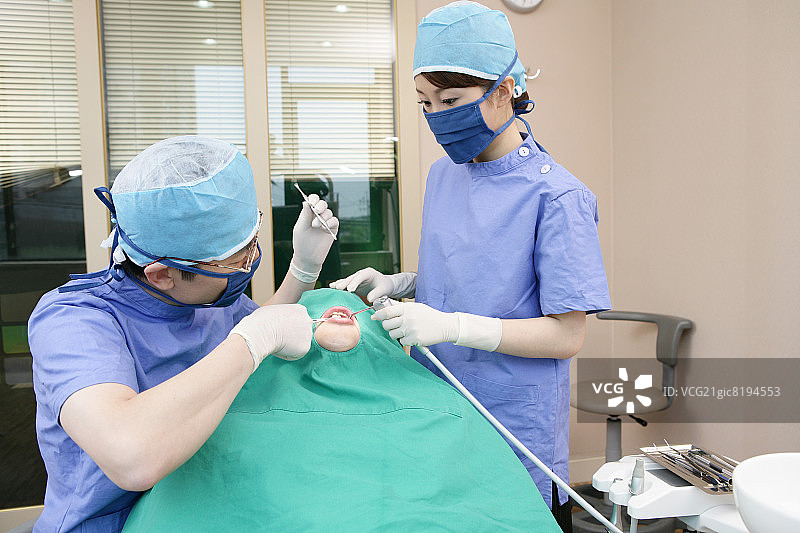 牙医和牙科助理在牙科诊所为患者做手术图片素材