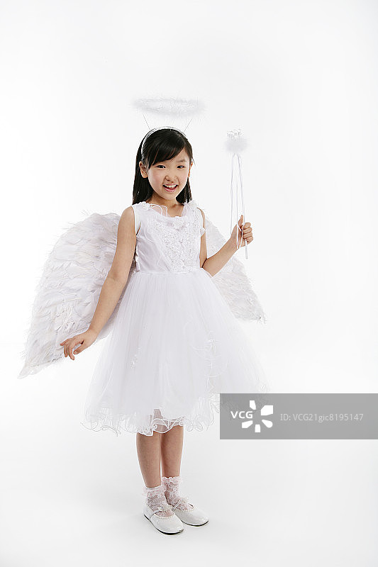 穿着仙女服装、手持魔杖微笑的女孩（12-13岁）肖像图片素材