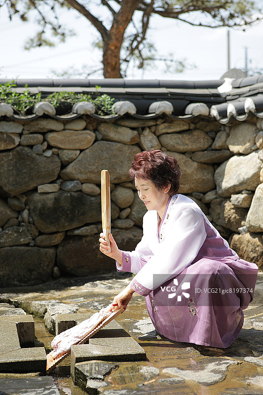 身穿韩国传统服装使用搓衣板的老年妇女图片素材