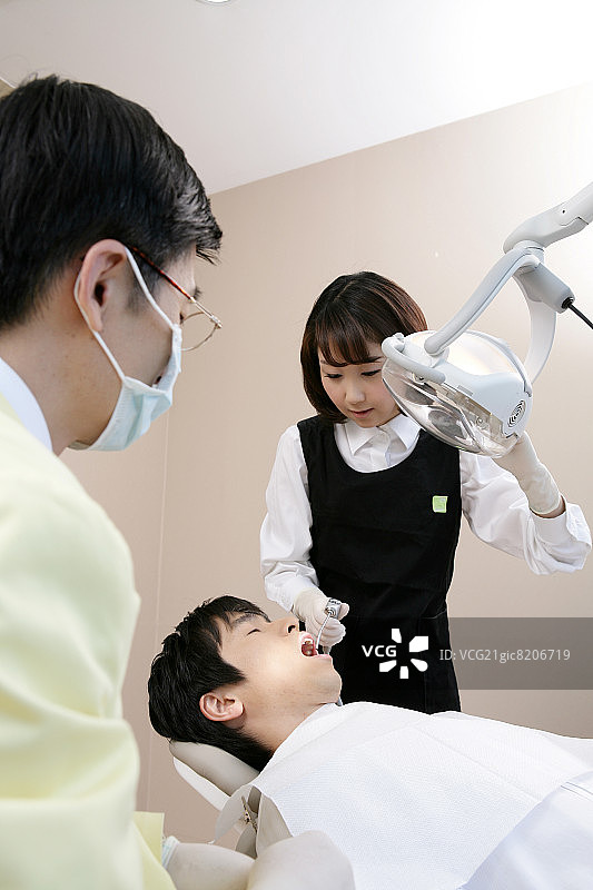 牙科助手用牙钻为患者进行手术图片素材