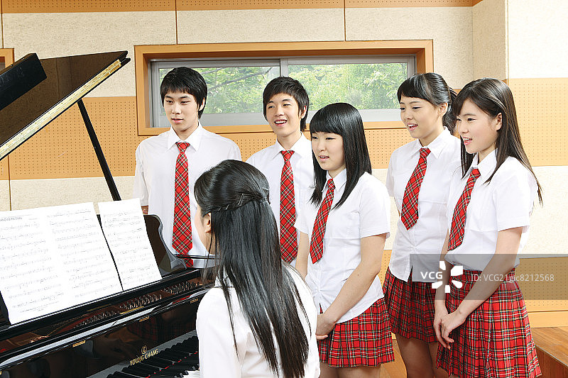 老师在课堂上弹钢琴时唱歌的学童图片素材