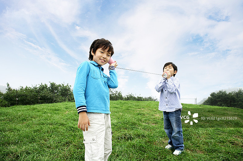 通过罐头电话交谈的男孩（6-11岁），面带微笑图片素材