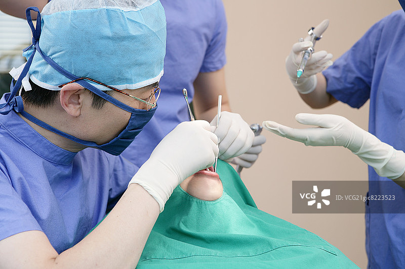 牙医和牙科助手在牙科诊所为病人进行手术图片素材