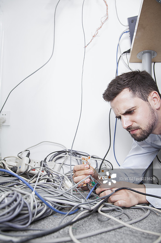 躺下试图整理电脑电缆的沮丧男人图片素材