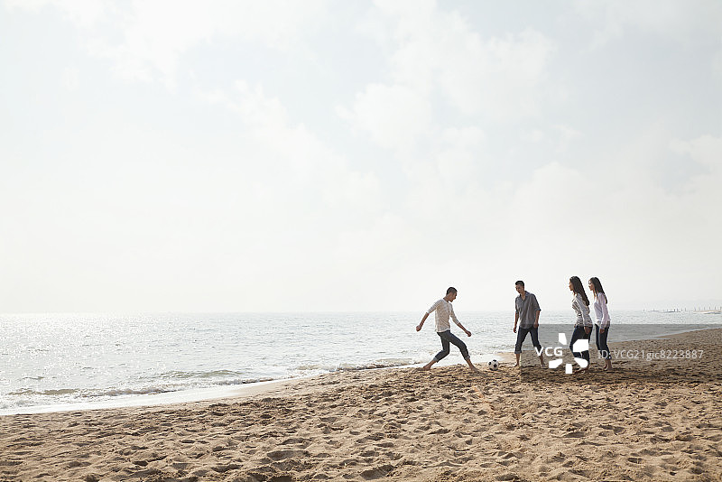 在海滩上踢足球的年轻朋友们图片素材