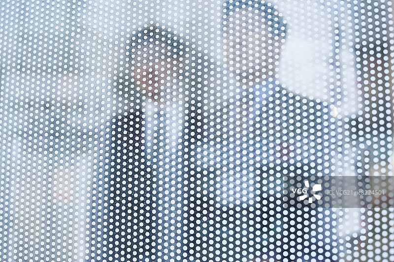 两位商人在玻璃墙后向外看，面容模糊图片素材