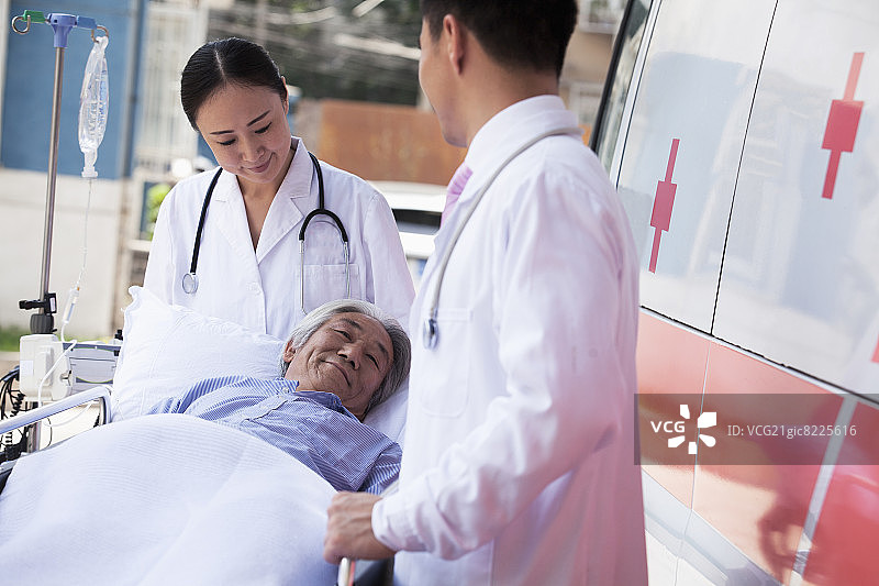 两名医生用担架将老年患者抬到救护车前图片素材