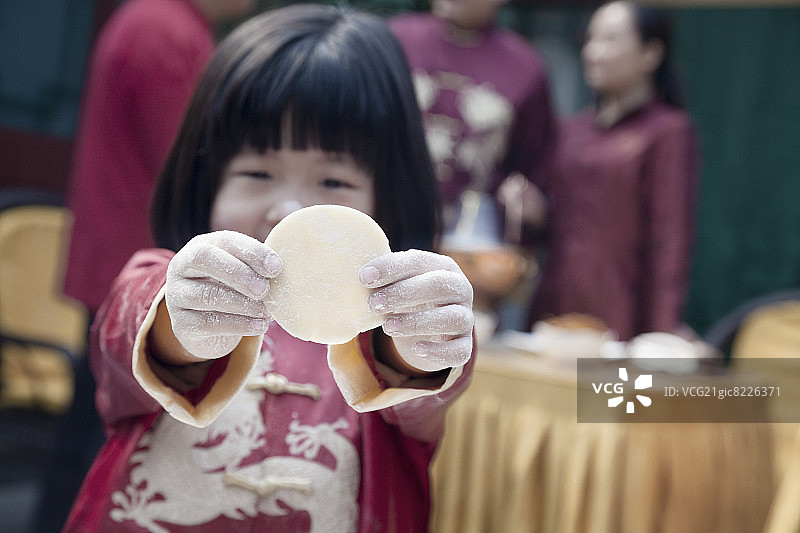 身着传统服饰的小女孩展示饺子皮图片素材