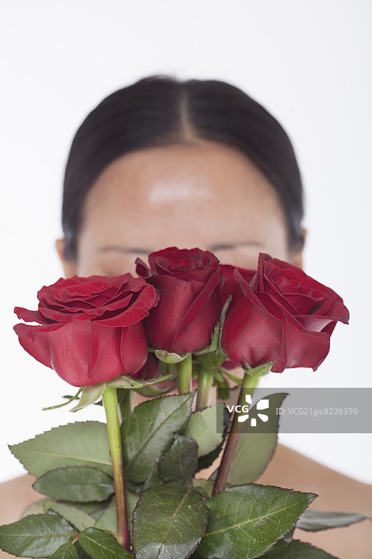 手捧红色玫瑰的赤膊女子，面部遮挡，影棚拍摄图片素材