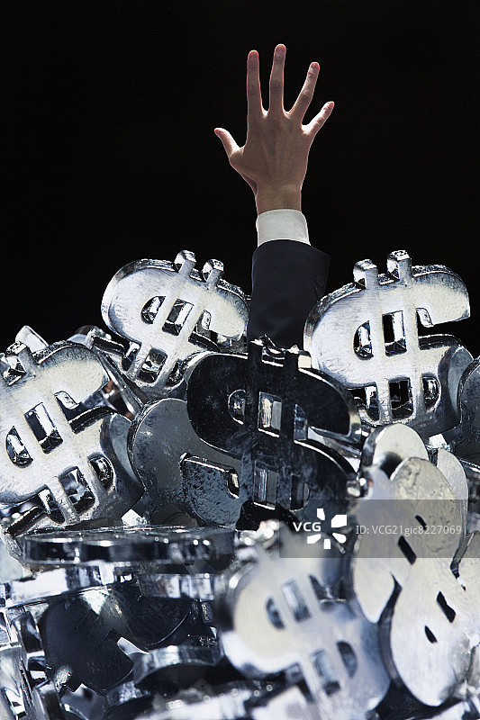 商人被埋在一大堆美元符号下，试图逃脱图片素材