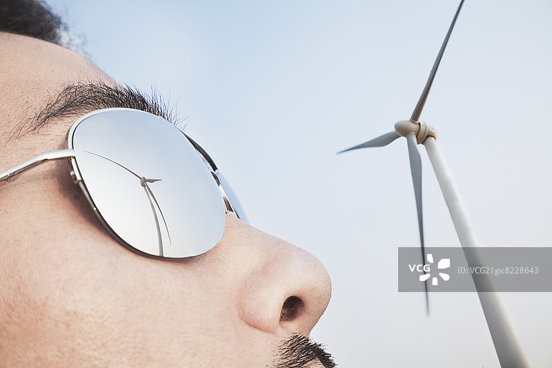 墨镜中反射着风力涡轮机的年轻男子面部特写图片素材