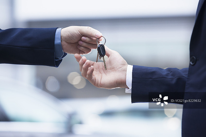 汽车销售员将新车钥匙交给年轻商人特写图片素材
