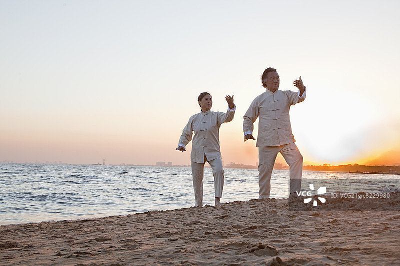 两位老人在中国海滩日落时练习太极拳图片素材