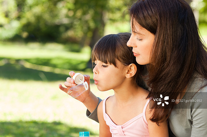 女孩和母亲在公园里吹泡泡图片素材