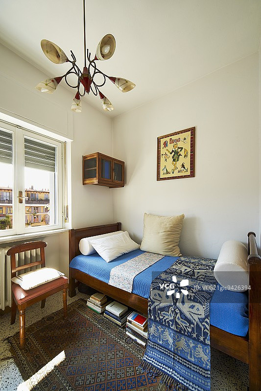 带有蓝色封面的30年代实木床和带有皮革座椅的椅子，床头柜下方是带有五十年代锥形灯罩的灯图片素材