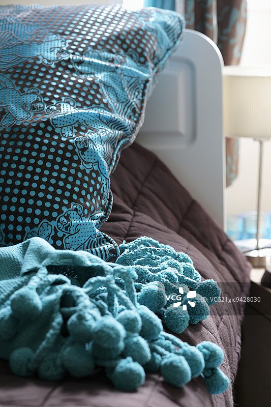 棕色和蓝绿色枕头与相配的带绒球毯子图片素材