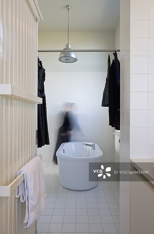 带毛巾架和独立式浴缸的散热器；金属杆上挂着深色衣物图片素材