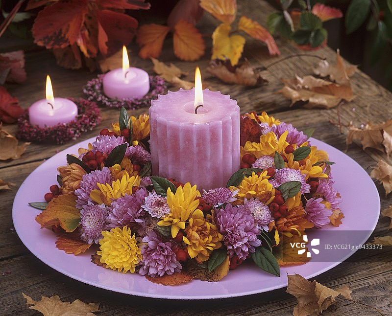 菊花和栒子花环与餐盘上的蜡烛图片素材