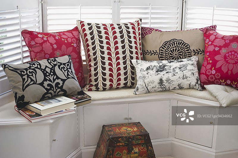 飘窗座位上带图案的彩色靠垫，配有嵌入式橱柜图片素材