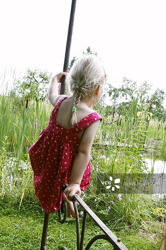 坐在花园凉亭栏杆上的金发女孩图片素材