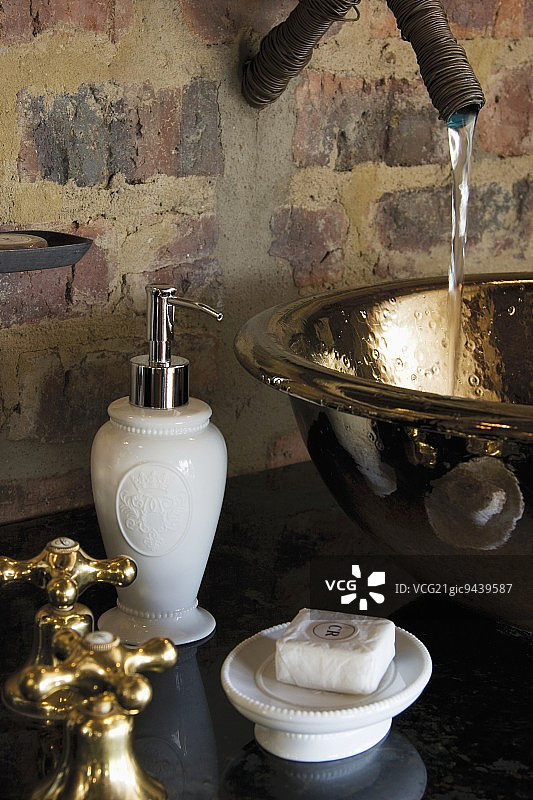 黄铜水槽流水，背景为砖墙图片素材