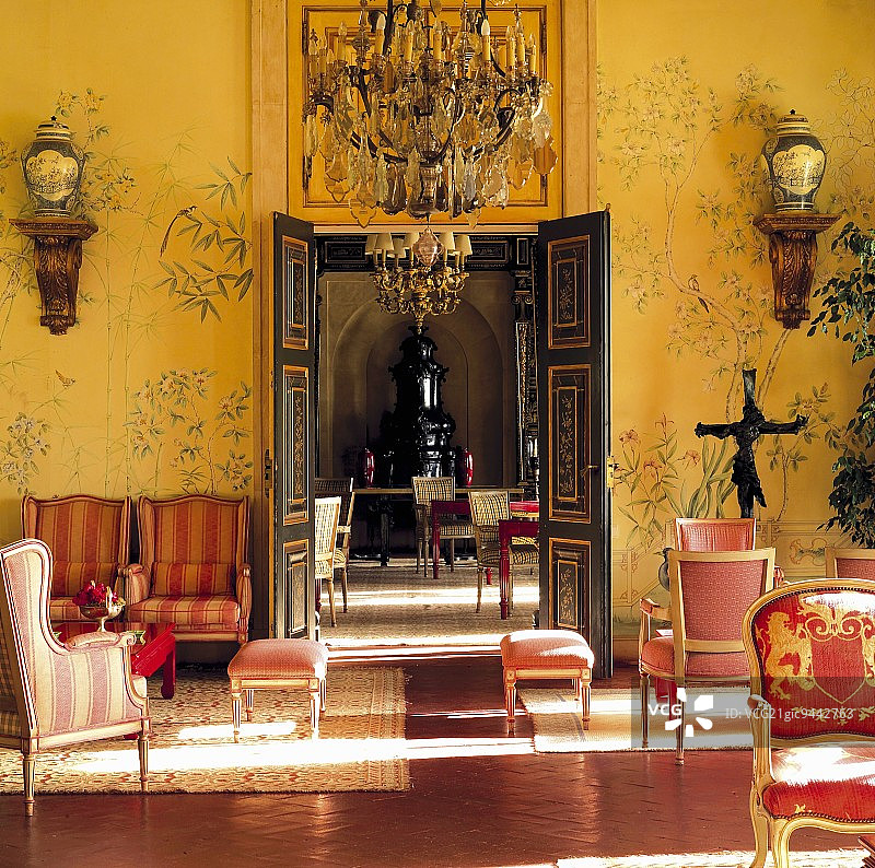 豪华酒店沙龙内，金色挂毯和中国图案墙壁前的红色洛可可式座椅图片素材