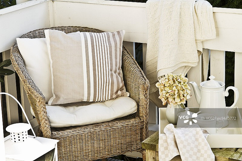 阳台上的午后小憩 - 柳条扶手椅，旁边茶几上放着茶具图片素材