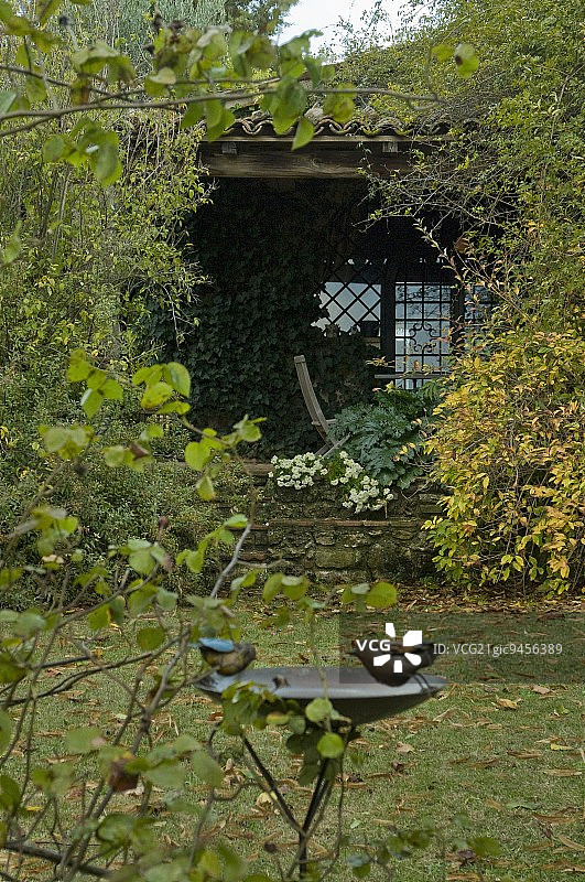 花园里长满青苔的小避暑小屋和鸟池图片素材