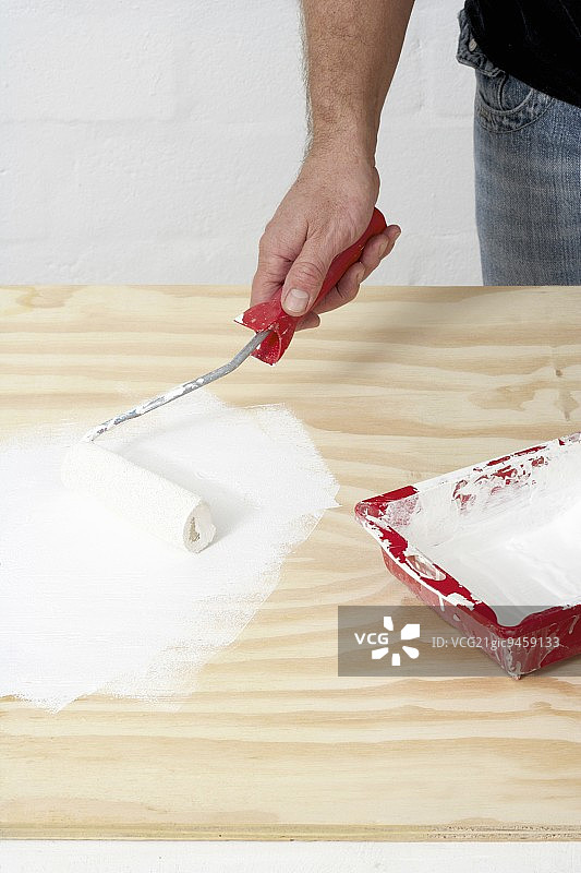 手持滚筒刷和工作台上的油漆托盘图片素材