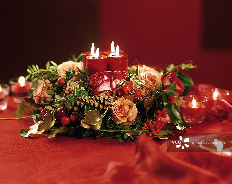 用玫瑰、金线和燃烧的蜡烛装饰的圣诞花环图片素材
