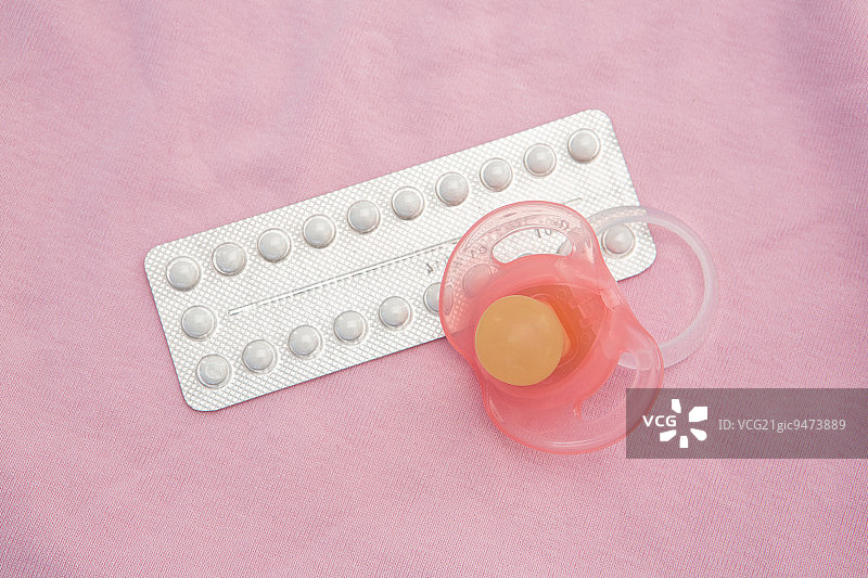 粉色毯子上的避孕药丸和粉色奶嘴图片素材