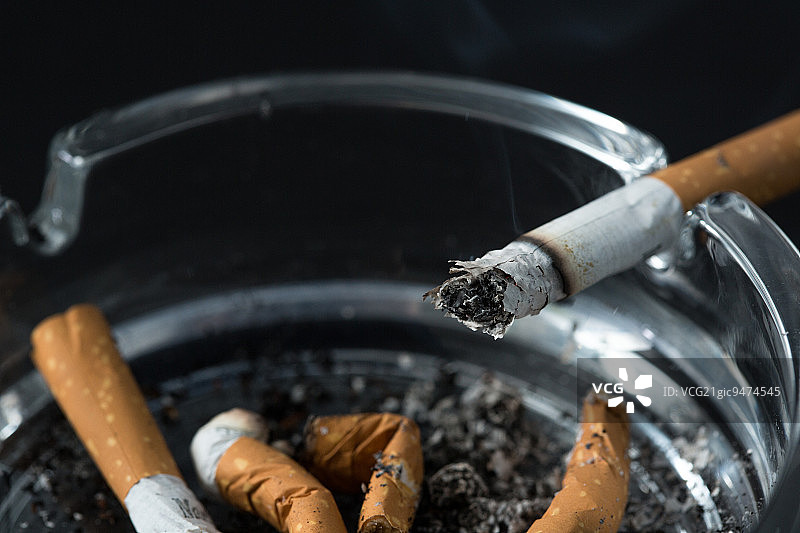 黑色背景烟灰缸中燃烧的香烟图片素材