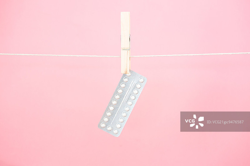 粉色背景悬挂的避孕药板图片素材