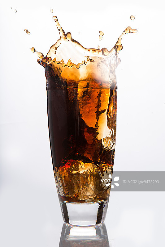冰块落入白色背景上的苏打水杯中图片素材