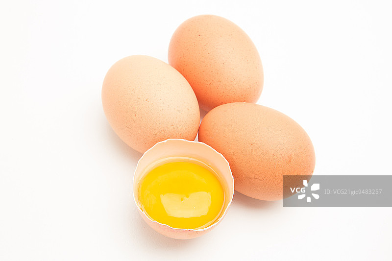 白色背景下半个蛋壳中的三个蛋黄图片素材