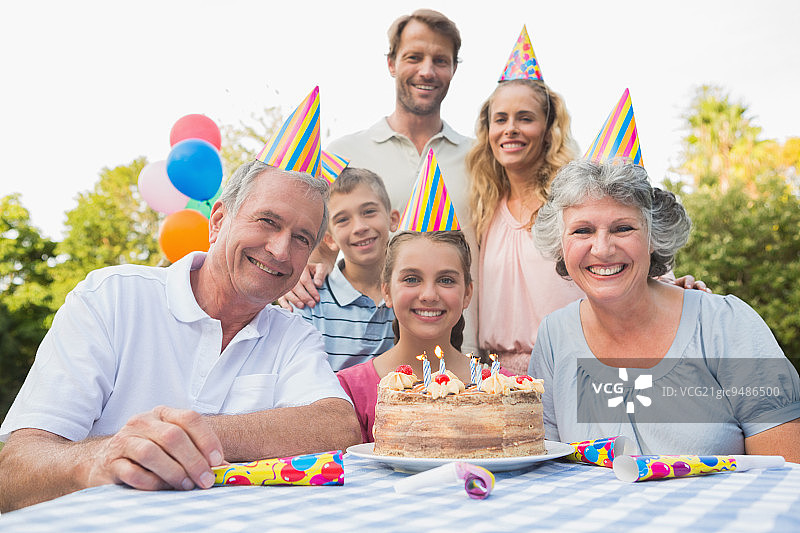 在户外野餐生日派对上对着镜头微笑的快乐家庭图片素材