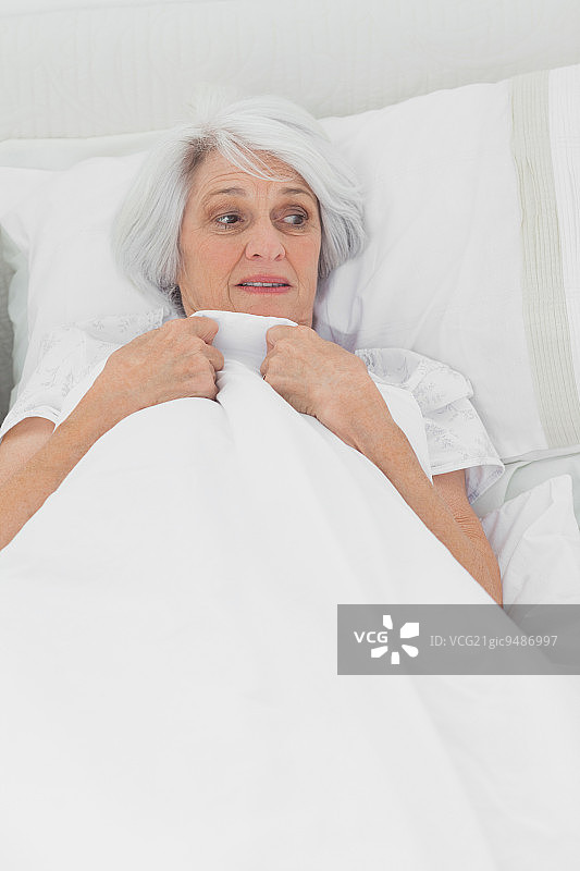 中年妇女在床上显得害怕图片素材