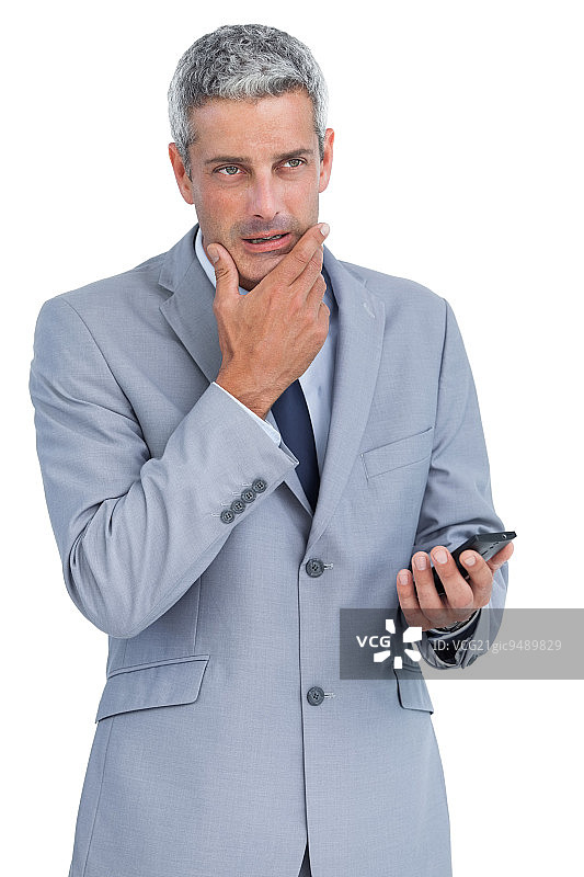 沉思的商人摸着下巴，拿着手机，背景为白色图片素材