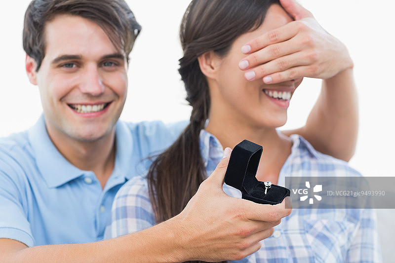 男子在沙发上遮住女友的眼睛并向她求婚图片素材