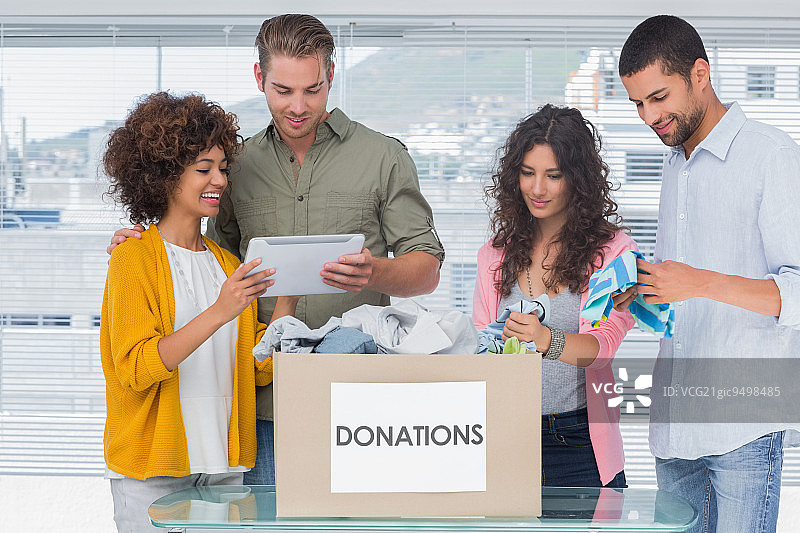 志愿者使用平板电脑从捐赠箱中取出衣服做慈善图片素材