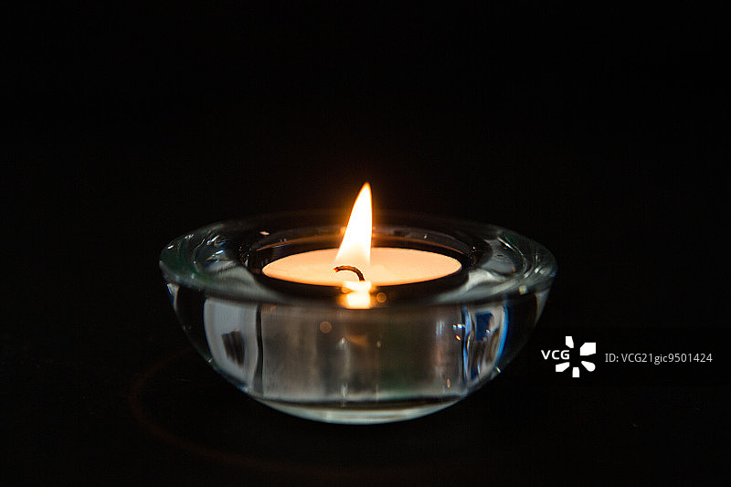 黑暗中玻璃烛台中点燃的蜡烛图片素材