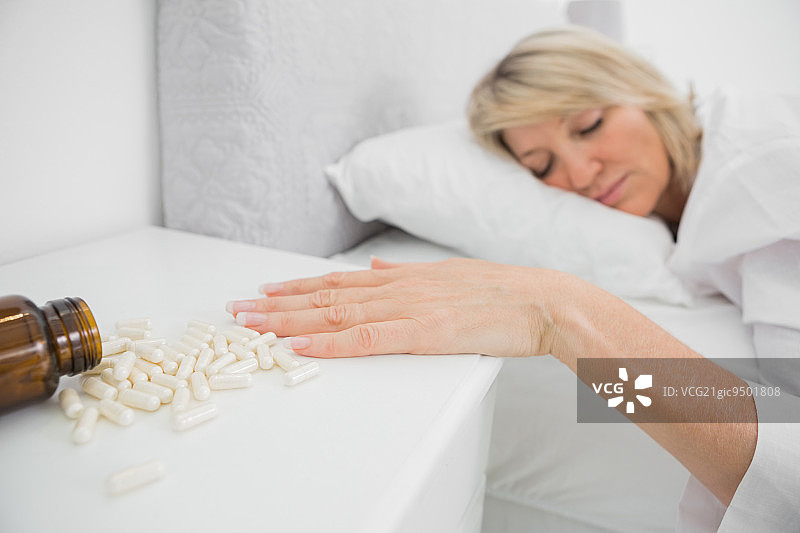 女人躺在床上，身旁有药丸图片素材