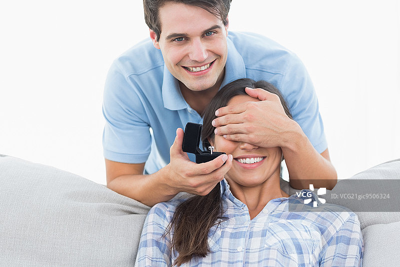 男人蒙住女友的眼睛，在沙发上向她求婚图片素材