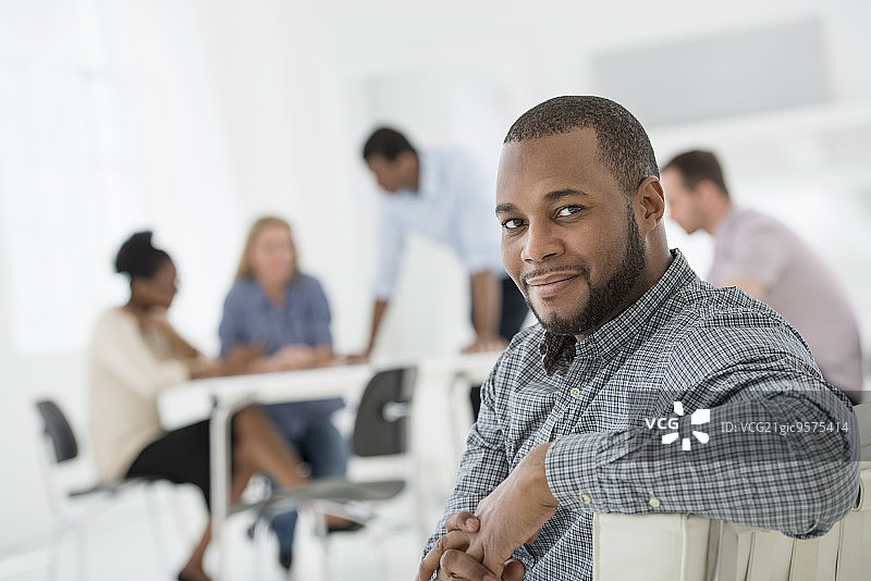采光充足的白色建筑内部，一群人正在开会，一人回头张望图片素材