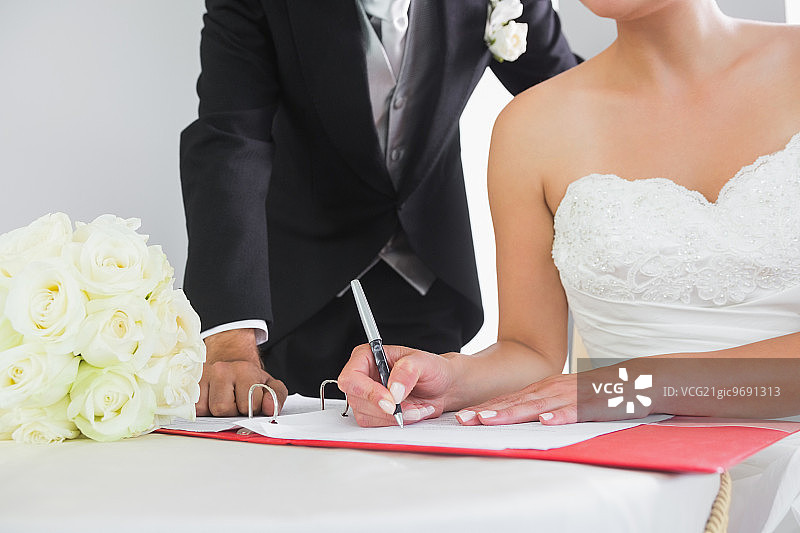 年轻夫妇坐在桌旁签署婚礼合同图片素材