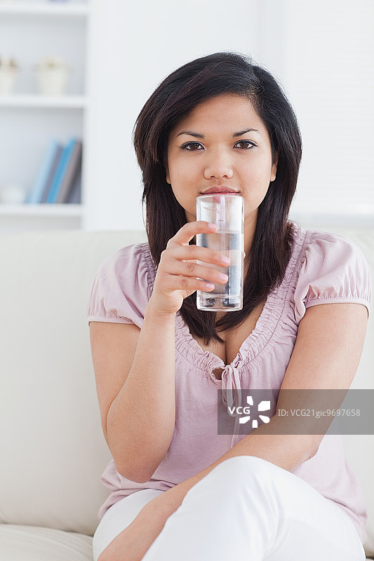 坐在客厅沙发上，拿着一杯水的女人图片素材