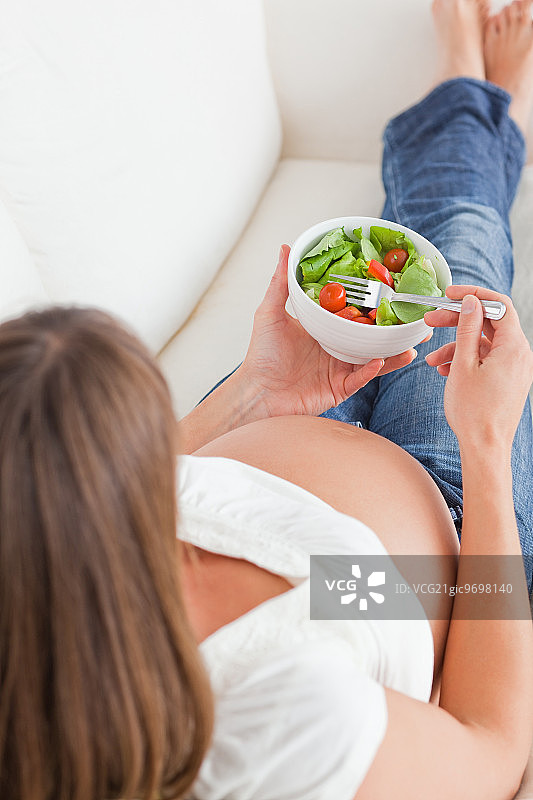 孕妇躺在沙发上吃沙拉图片素材