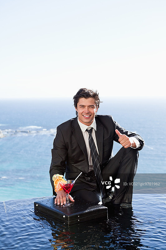 商务人士手提公文包，拿着鸡尾酒并竖起大拇指图片素材